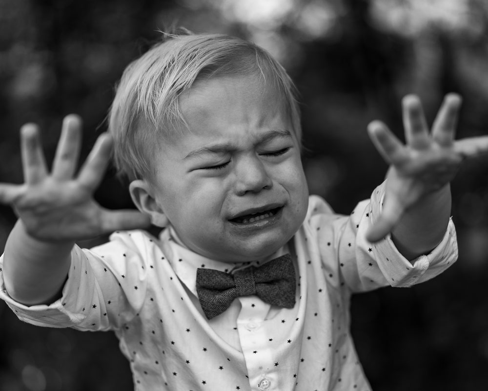 Black and white photo of child that might be about to sneeze.